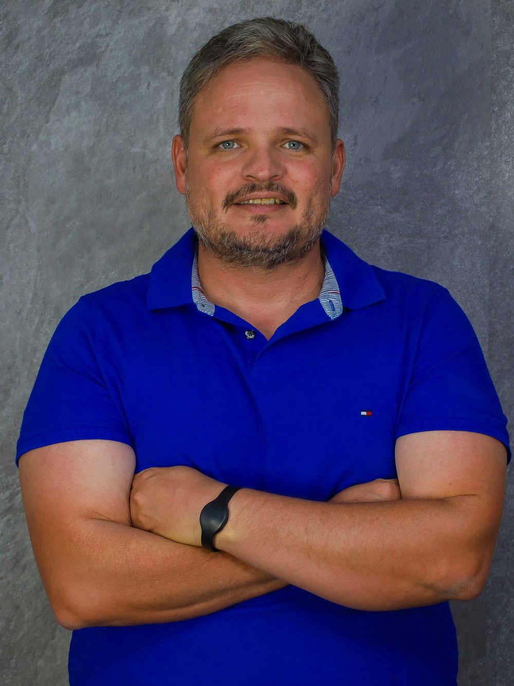 Retrato de Rafael Campelo, de braços cruzados, em camisa polo azul.